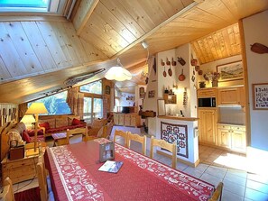 A cozy cabin interior with a dining area, wooden furniture, and a kitchen.