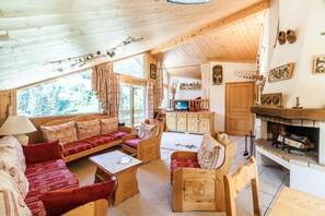 Un intérieur de chalet chaleureux, avec des meubles en bois, une cheminée et un téléviseur dans le salon.