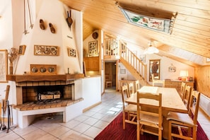 A cozy, rustic interior with a fireplace, wooden furniture, and a staircase leading to an upper level.