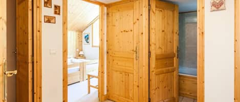 A wooden room with a bed, a small table, and a shower area.