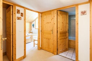 A wooden room with a bed, a small table, and a shower area.