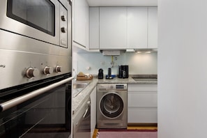 Une cuisine équipée d’un four, d’un micro-ondes et d’un lave-linge intégrés.