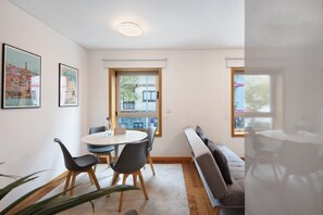 Ein modernes Zimmer mit einem runden Esstisch, Stühlen, einer Bank, einem Fenster und zwei gerahmten Bildern an der Wand.