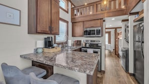 A kitchen with granite countertops, wooden cabinets, a built-in microwave, and a stainless steel refrigerator.