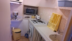 A compact kitchen with a microwave, toaster, and gas stove. - Seaside vacations (Coti-Chiavari)