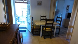A dining area with a wooden table and chairs, a wicker basket, and a view of the outside. - Seaside vacations (Coti-Chiavari)