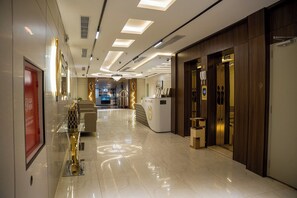 Un moderno vestíbulo de hotel con piso limpio y pulido, un mostrador de recepción y un conjunto de ascensores.