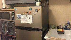 Une cuisine équipée d’un réfrigérateur en acier inoxydable, d’un four à micro-ondes, d’un grille-pain et d’un évier avec un égouttoir à vaisselle vert.