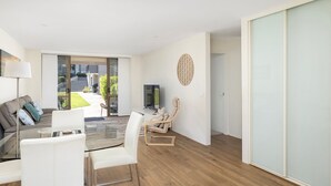Ein modernes Wohnzimmer mit einem Glastisch, weißen Sofas und einem Fernseher.