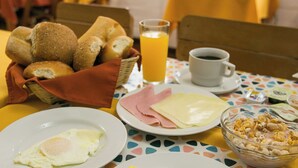 A breakfast setting with bread, eggs, and a bowl of cereal on a table with a colorful tablecloth. - Casa de Baraybar (Lima)