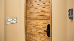 A wooden door with horizontal slats and a black handle. A sign with decorative borders and text is visible on the wall to the left. - Casa de Baraybar (Lima)