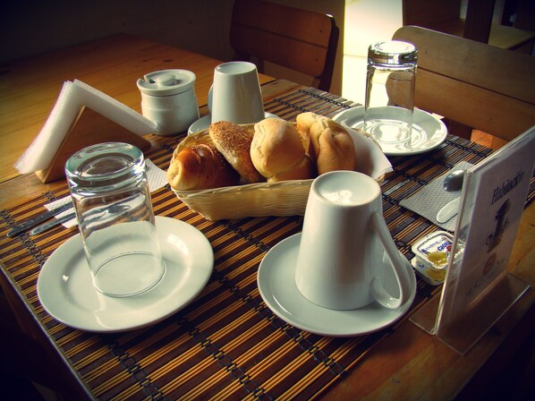 A dining table with a basket of bread, two cups, a glass of water, and a plate of food. - Casa de Baraybar (Lima)