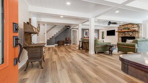 Un vaste espace de vie doté d’un plancher en bois, d’un escalier et d’une cheminée en pierre.