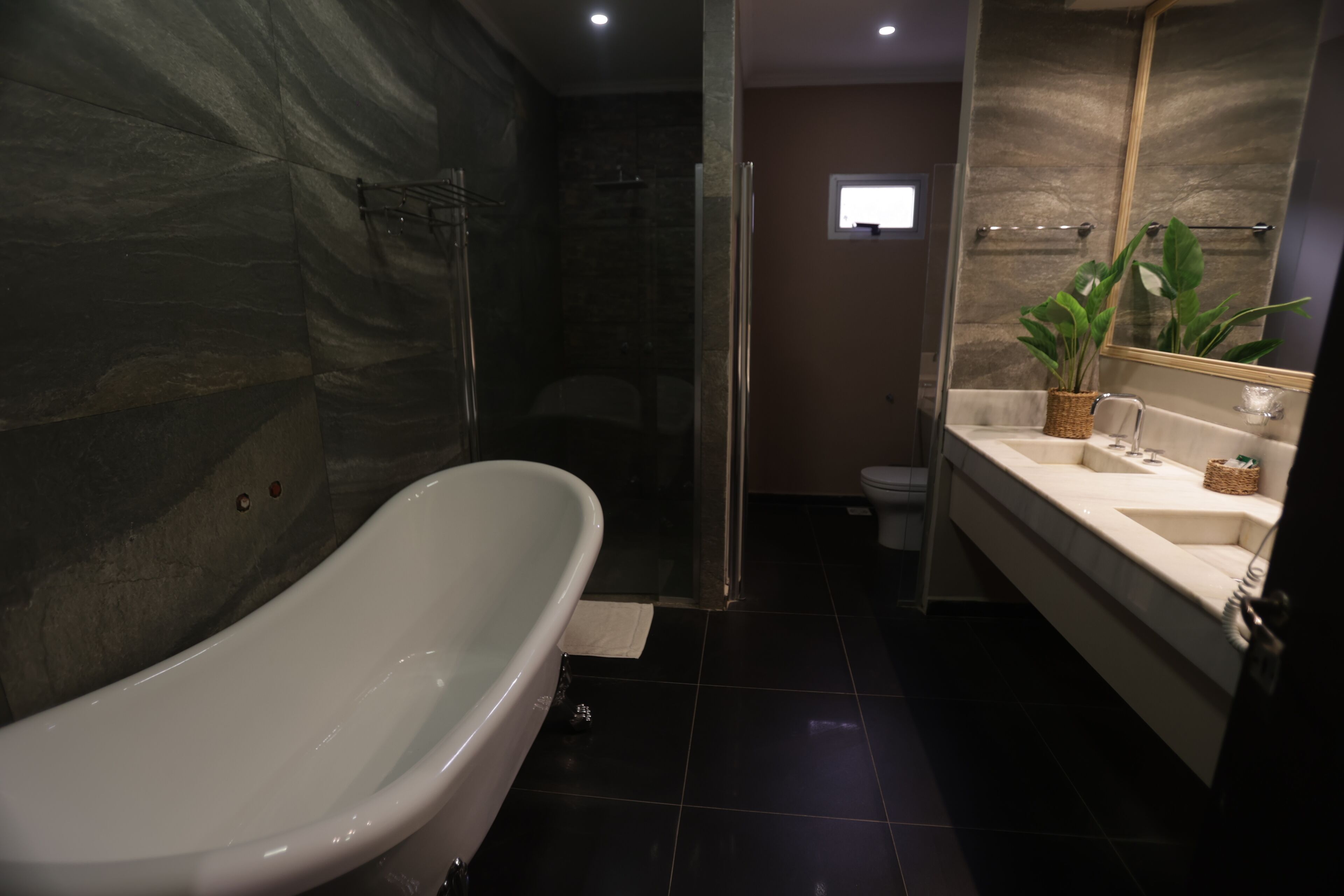 Une salle de bain moderne comprenant une baignoire sur pieds, une douche, des toilettes et un meuble-lavabo avec un miroir.