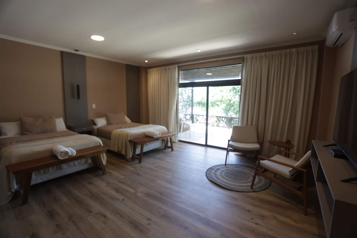 Habitación de hotel con dos camas, un escritorio, una silla y una televisión.