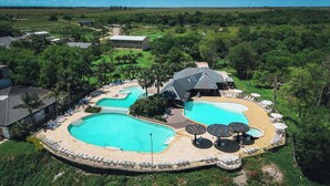 Een resort met meerdere zwembaden, ontspanningsruimtes en een groot huis.
