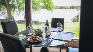 Een eettafel voor twee personen met uitzicht op een meer en groen.