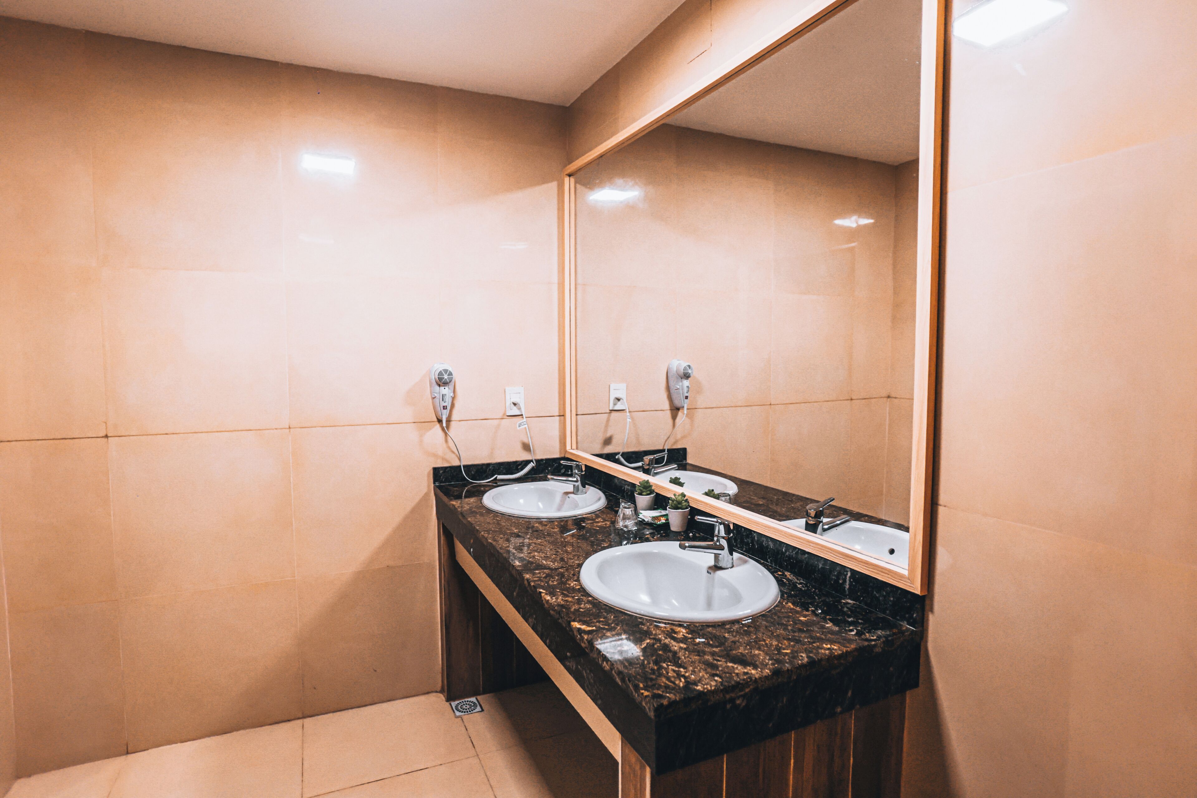 A bathroom with two sinks, a mirror, and a bench.