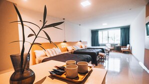 Een hotelkamer met een houten tafel, twee bedden, een groot raam en een plant.