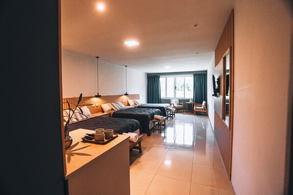 Una habitación de hotel con tres camas, un escritorio y una bandeja con objetos, además de una silla.