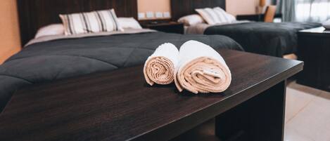 Ein Hotelzimmer mit zwei Betten, dunklen Holzkopfteilen und einem Nachttisch aus Holz mit einer Lampe.