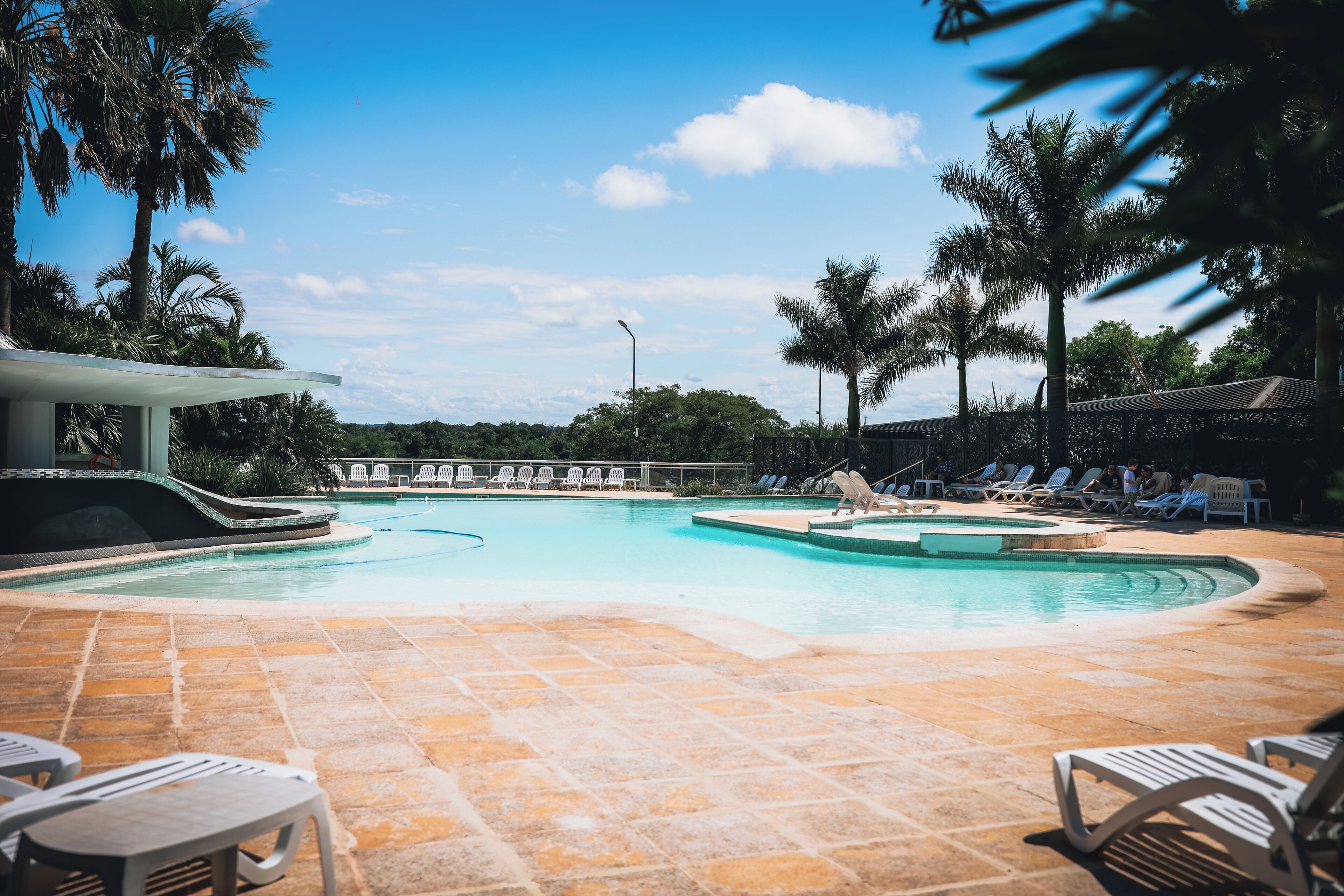 A pool area with lounge chairs and a covered seating area.