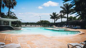 A pool area with lounge chairs and a covered seating area.
