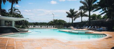 A pool area with lounge chairs and a covered seating area.