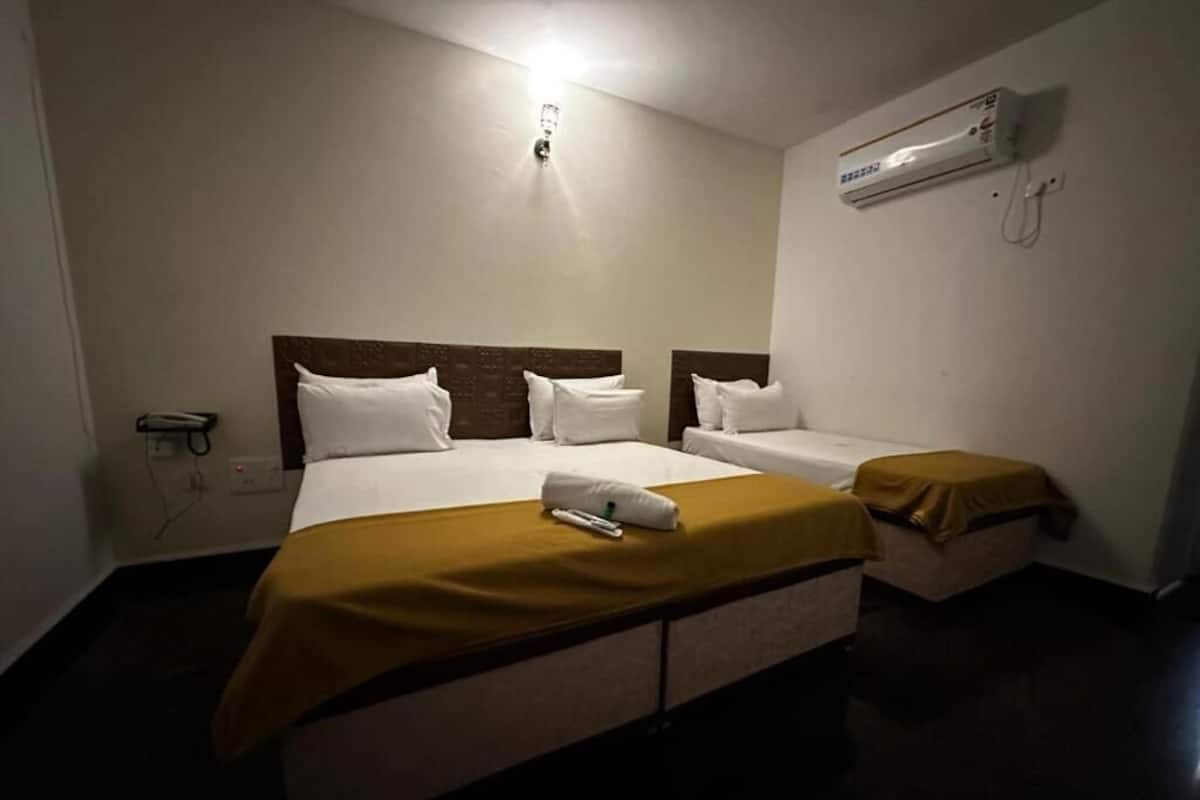 Une chambre d’hôtel avec deux lits, une table de chevet, un appareil de climatisation et une prise électrique murale.