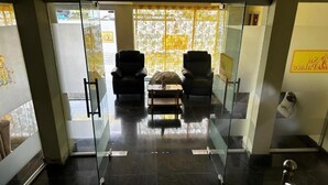 Un área de recepción con dos sillones, una mesita y una partición de cristal.