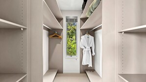 A walk-in closet with a window, shelves, and a hanging robe. - Birdsong House, a contemporary family home close to the beach. (Kaiteriteri)