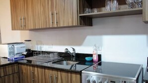 A kitchen with wooden cabinets, a stainless steel stove, a sink, and a dish rack. - Sabana Sur House (San José)
