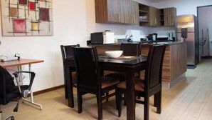 A modern kitchen with wooden cabinets, a dining table with chairs, and a small island with a sink. - Sabana Sur House (San José)