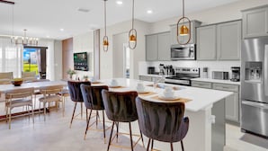 Una cocina moderna con electrodomésticos de acero inoxidable, una isla grande e iluminación colgante.