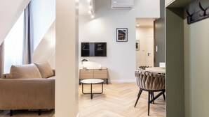 A modern living room with a sofa, a round table, and a TV mounted on the wall. - Dom Pod Kotwicą (Kraków)