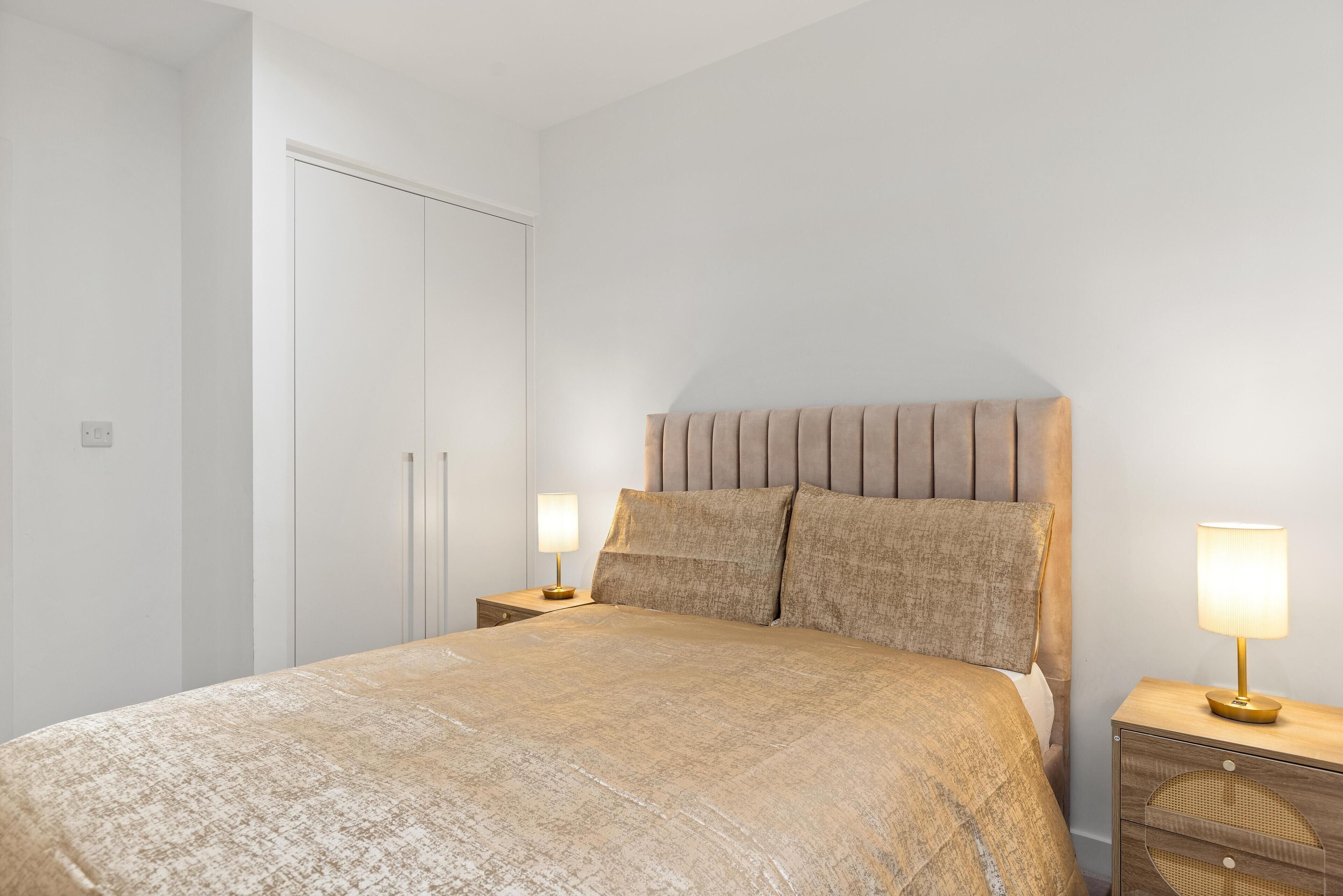 A bedroom with a bed, nightstands, a wardrobe, and a lamp.