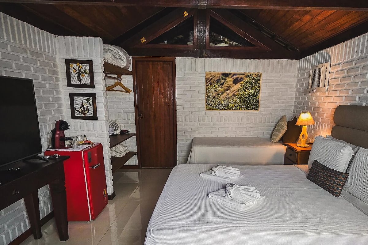 Ein Hotelzimmer mit Bett, Fernseher, einer roten Minibar, einer Holztür und einem Bild an der Wand.
