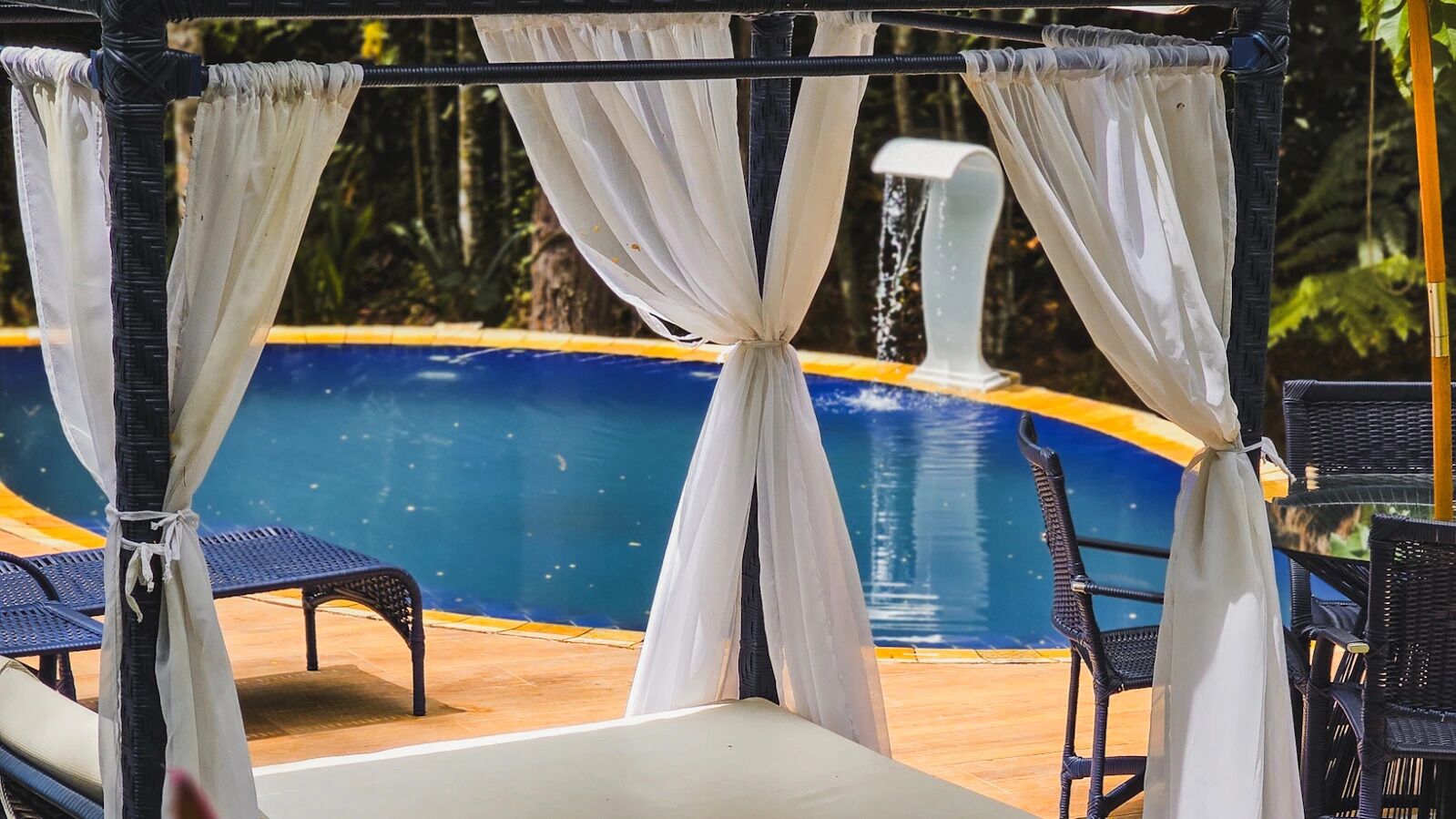 Zona junto a la piscina con una pérgola, sillas de descanso y una pileta.