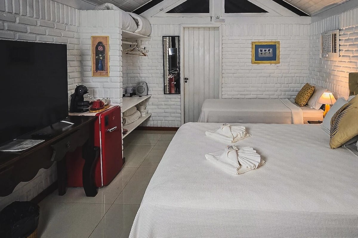 Ein Hotelzimmer mit einem Bett, einem Schreibtisch mit Fernseher, einem roten Schrank und einer weißen Ziegelwand.