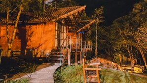 Un edificio de madera con una escalera que conduce a un balcón, rodeado de árboles.