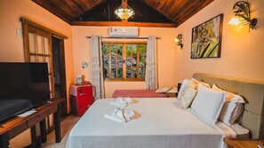 A hotel room with a bed, a TV, a small red fridge, and a window with curtains. - Pousada Conde Redondo (Nova Friburgo)