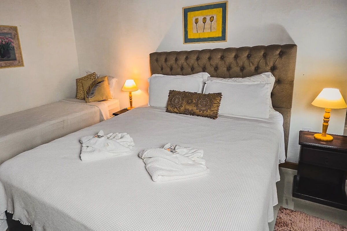 Ein Hotelzimmer mit zwei Betten, jeweils mit weißen Bettwäsche und Kissen, einer gepolsterten Kopfstütze und einem Nachttisch mit Lampe.