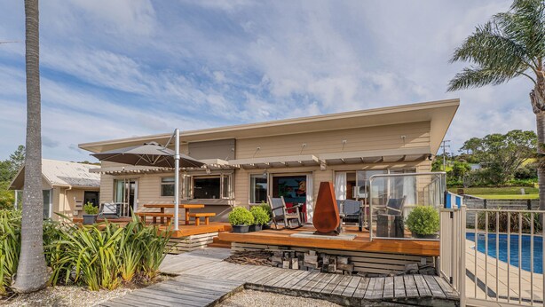Una casa moderna con terraza, mobiliario exterior y piscina.