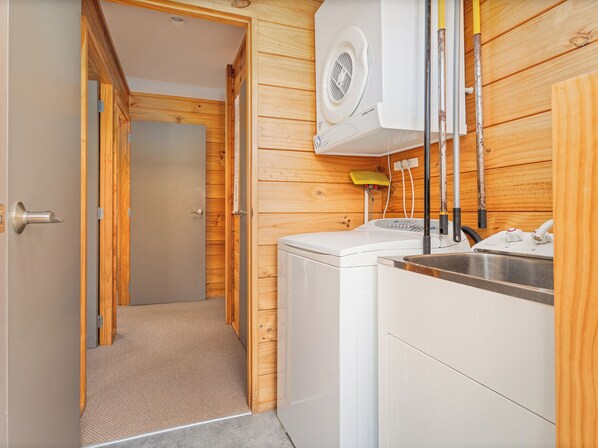 Un espacio de lavander ía reducido con lavadora, pileta y pared de madera.