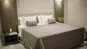 Une chambre moderne avec un grand lit, une table de chevet et une commode.
