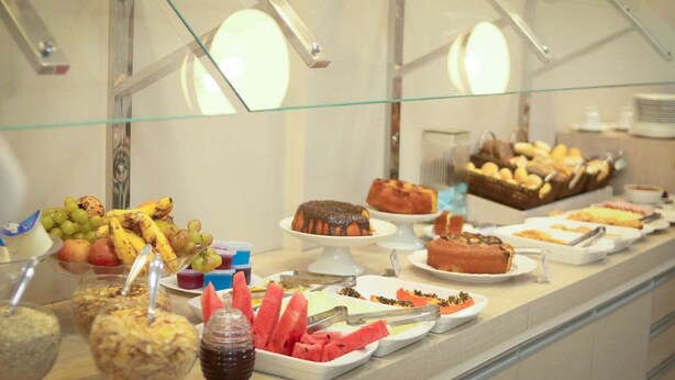 Un buffet proposant une variété d'aliments, notamment des fruits, des desserts et des boissons.