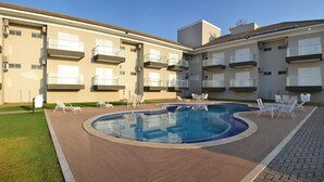 Un immeuble d’appartements moderne doté d’une piscine, d’un espace extérieur aménagé et de balcons.
