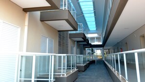 Un couloir doté d’un plafond en verre, de rampes en métal et d’un sol carrelé.