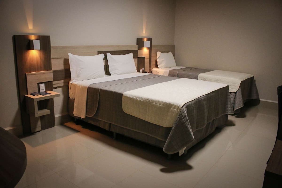 Ein Hotelzimmer mit zwei Betten, jeweils mit Holz Kopfteil und Nachttischen.