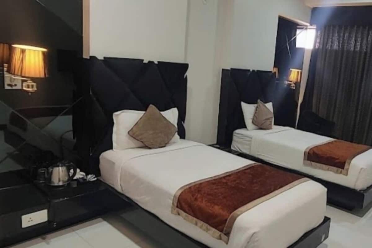 Ein Hotelzimmer mit zwei Betten, einem Flachbildfernseher, einer Kaffeemaschine und einem kleinen Tisch.